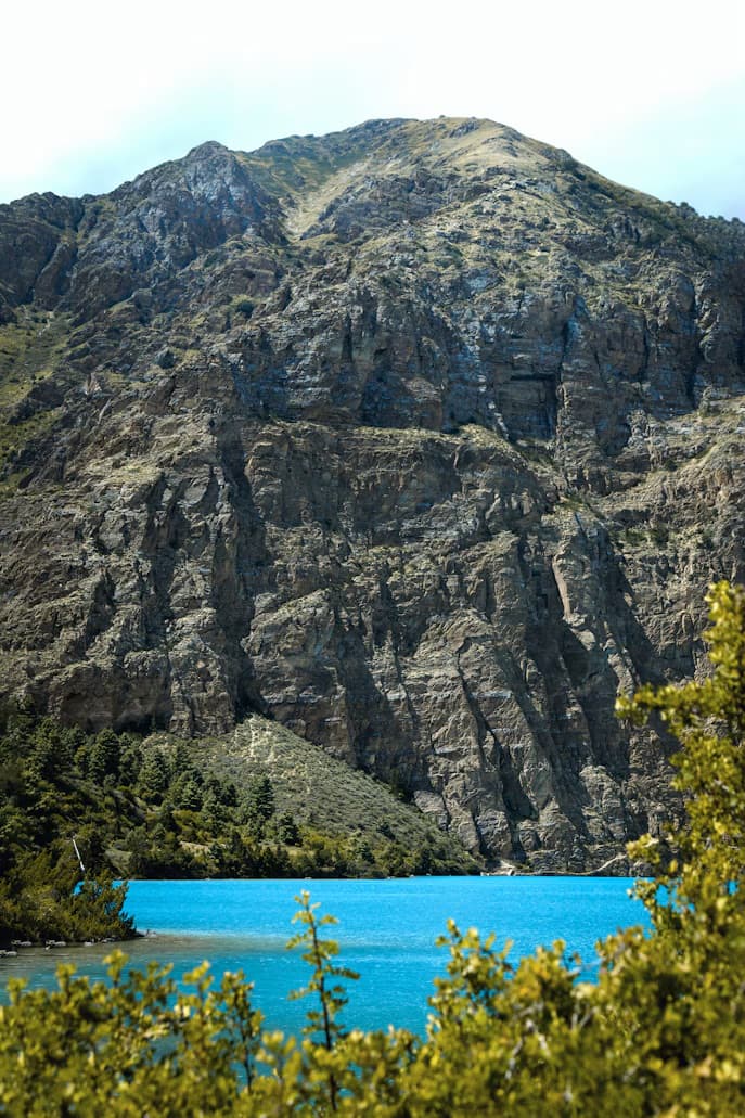 A turquoise lake below a rocky mountain in Nepal